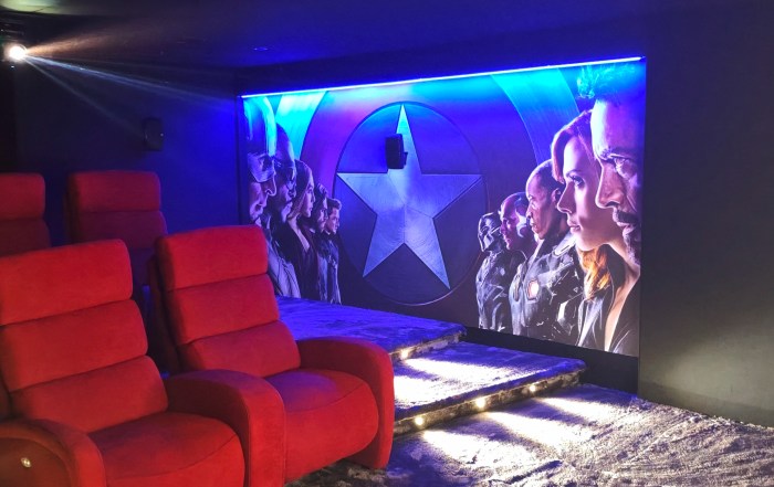 Salle de cinéma privée dans un Airbnb à Cholet : cinq fauteuils sur estrade face au mur de scène rétroéclairé